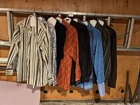 Photo of hanging men's shirts showing striped, checked, and solid color long-sleeve button-up shirts.