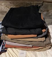 Stack of 10 pairs of men's casual and nice pants folded, assorted neutral colors including black, gray, tan, and brown shades, showing condition and variety in colors.