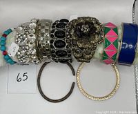 Photo showing ten modern bracelets on a display rod, variety of hinged cuffs, bangles, and elastic bracelets.