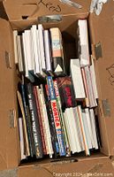 Top view of a cardboard box filled with various graphic novels and books, showcasing titles like Harry Potter, Marvel, and Star Wars.