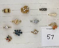 Top view of all 12 rings showing front face designs including stones and enamel details