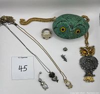 Overview of all items including painted owl rock, various owl jewelry including necklaces, pendants, rings, and small charms.