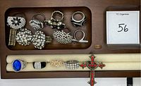 Photo of 11 rhinestone rings and 1 cross pendant necklace displayed in a wooden organizer and on a ring holder bar.
