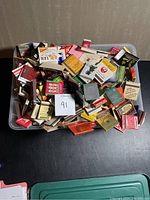 Large plastic bin filled with vintage matchbooks in various designs and colors.