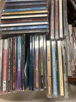 Close up of various stacked CD jewel cases showing titles such as John McDermott, Paul Simon, Peter Paul and Mary, and others.