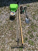 Full lot showing rake, spade, trowels, hoe, garden clippers, and a container near green yard scoops.