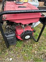 Side view of red gasoline generator showing engine and recoil starter.