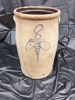 Front view of large 8 gallon stoneware crock showing stamped blue bee sting design.