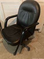Front view of black office chair showing padded seat, backrest, and armrests on a wheeled base.