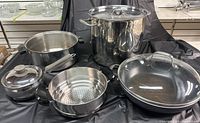 Overview of all cookware items including pots, strainer, and frying pan with lids.