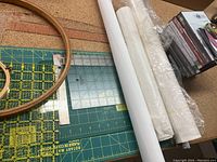 Photo showing wooden crafting hoops alongside various quilting rulers and cutting mats on a table.