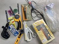 Overview of sewing and craft tools including textile tool kit, rotary cutters, scissors, tape measures, glue sticks, hand drill, and pen.