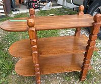 Full side angle showing the three shelf tiers and the rounded ends with the carved support columns and round finials.