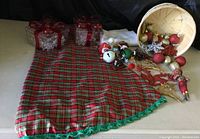 View of entire collection showing tartan tablecloth, ornament basket with glittered baubles and snowflakes, and two clear acrylic gift boxes with snowflake lights.