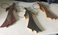 Top view of three wooden angels with wire wings laid out on a flat surface