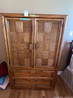 Front view of the wooden armoire wardrobe cabinet showing double patterned doors and drawer base.