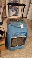 Full front view of blue dehumidifier with handle extended and intake grille
