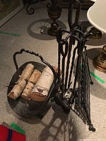 Wrought iron coal scuttle with handle holding birch logs.