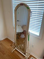Full view of the floor mirror positioned near window and door, showing the entire mirror including base stand.