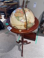 Full view of the vintage globe on the wooden tripod stand, showing the globe's map and stand details.