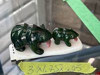 Front view of both green jade bear figurines positioned on a white stand with size note.
