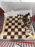 Marble chessboard with pieces packed in a white cardboard box, showing board squares and stones of different colors.