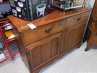 Side angle view of the maple wood sideboard showing the left side drawer and cabinet doors with metal hardware.