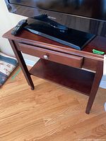 Front view of wooden sofa table with drawer, showing polished wood finish and metal knob on drawer.