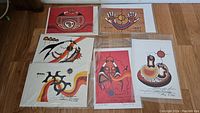 Six unframed Jackson Beardy prints laid out on wooden floor
