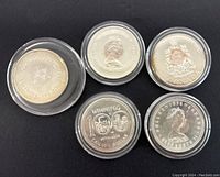 Top view of five vintage collectible Canadian silver coins showing front and back design details in protective cases