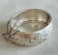 Front view of engraved sterling silver bangle with safety chain draped
