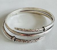 Silver snake bangle coiled, showing snake head and tail ends detail and marking inside