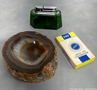 Lot laying on gray surface showing agate ashtray, green Bentley lighter, and pack of 702 Gold Tip cigarettes