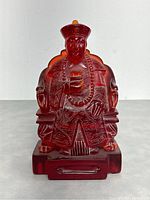 Front view of the pressed amber empress figurine showing detailed facial features and ornate robes.