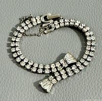 Close-up of Sherman rhinestone bracelet coiled on gray surface showing rhinestone details and clasp.