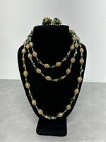 Full front view of necklace with matching earrings displayed on black velvet stand