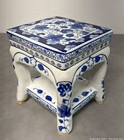 Front and side angled view of the hexagonal ceramic plant stand showing blue floral patterns and curved legs.