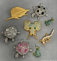 Lot photo showing eight vintage brooches: dinosaur, turtles, elephant, frogs, and salamander lizard.