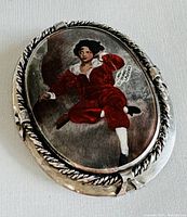 Front view of the sterling silver oval brooch featuring the enamel painting of 'The Red Boy' in red costume with white collar and cuffs.