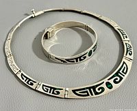 Choker and bracelet laid flat on grey surface showing detailed design and closure.