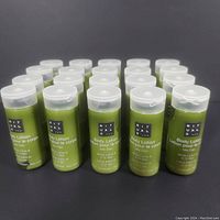 Twenty green Rituals body lotion bottles arranged on a black surface, showing front labels including product name and scent.