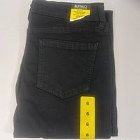 Folded pair of black jeans with visible back pocket and size 6 sizing label.