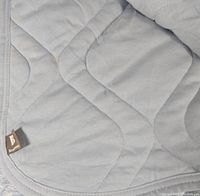 Close-up photo showing light blue quilted fabric with wave pattern stitching and Brookstone brand tag