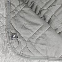 Photo showing folded corner of grey quilted cooling blanket with visible corner stitching and Brookstone tag