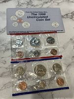 Two images showing the full 1998 United States Mint Uncirculated Coin Set with coins sealed in original plastic sleeves inside a light blue collector's envelope.
