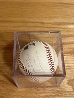 View of the baseball inside clear acrylic case showing handwritten dedication and inscriptions about the 2003 Giants Championship.