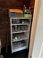White shelf with boxed and loose Ball Quilted Crystal mason jars and lids in a wood-paneled room.