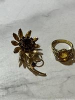Photo of gold filled ring and floral pendant showing both items on a flat surface.