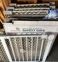 Photo showing a Summer Infant Central Station Safety Gate with plastic diamond mesh and locking mechanism, parts and packaging visible.