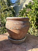 Side view of large vintage terracotta planter with carved decorative floral band, placed outdoors.